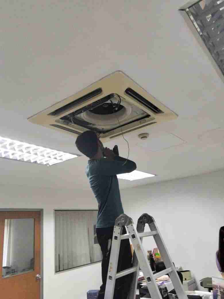 Technician repairing a leaking cassette aircond