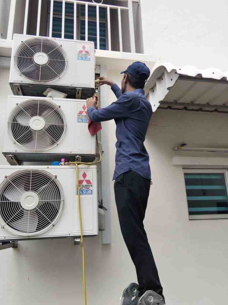 Technician servicing an outdoor aircond unit